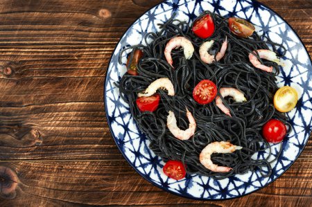 Téléchargez les photos : Spaghettis de haricots noirs végétaliens avec crevettes et tomates sur fond en bois. Photographie alimentaire. - en image libre de droit