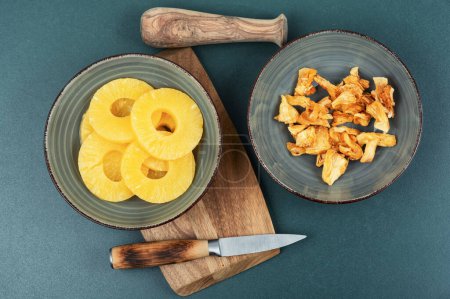 Téléchargez les photos : Ananas secs et frais dans des bols. Ananas aux bonbons, fruits confits. Collation aux fruits. - en image libre de droit
