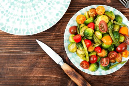 Photo for Salad of roasted brussels sprouts, tomatoes and green beans on a rustic wooden table. Flat lay with copy space. - Royalty Free Image