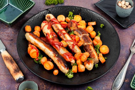 Photo for Baked or grilled turkey sausages with roasted carrots on the plate. German BBQ menu. - Royalty Free Image