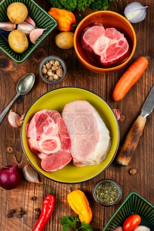 Photo for Juicy raw piece meat and vegetables on rustic wooden table. Set of ingredients for soup or borscht. - Royalty Free Image