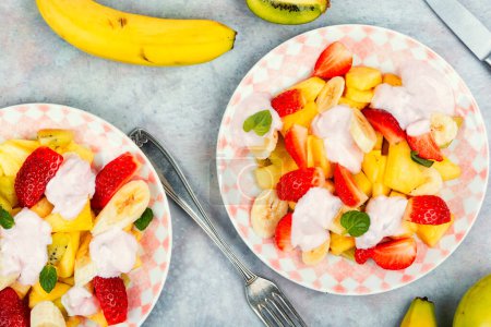Photo for Fresh fruit salad of strawberries, pineapple, banana, kiwi and yogurt. Healthy breakfast. Top view. - Royalty Free Image