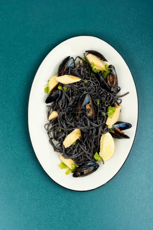 Black seafood pasta with mussels, clams in white plate. Top view. Mediterranean pasta vongole.