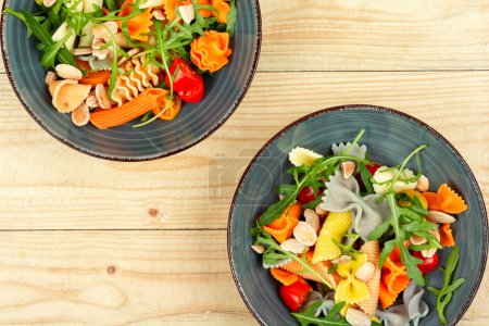 Téléchargez les photos : Salade aux tomates fraîches, herbes et pâtes dans une assiette sur une table en bois sombre . - en image libre de droit