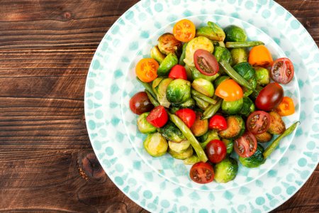 Foto de Ensalada de coles de Bruselas asadas, tomates y judías verdes. Concepto de comida vegana saludable. Piso con espacio de copia - Imagen libre de derechos