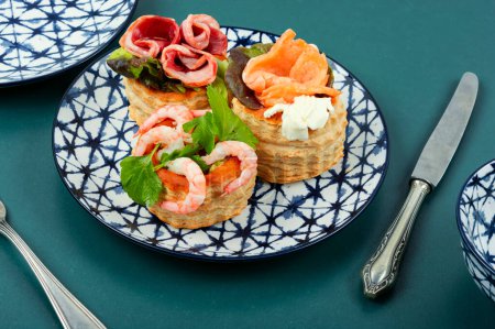Photo for Puff pastry tartlets with fish, shrimp and bacon on a plate on the table. - Royalty Free Image