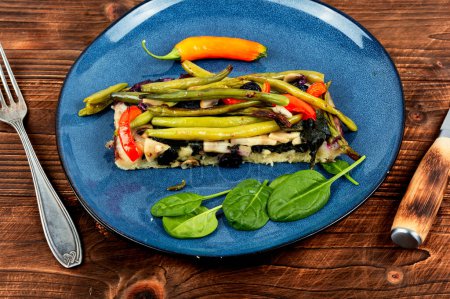 Stück Gemüse hausgemachte Torte mit grünen oder Buschbohnen und Paprika auf rustikalem Holzgrund.