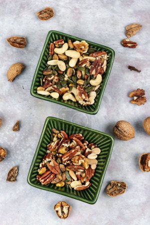 Téléchargez les photos : Mélange de noix sur une table en céramique. Superfood. Concept de nourriture végétarienne. Collations santé. - en image libre de droit