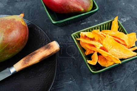 Téléchargez les photos : Morceaux de mangue séchés avec couteau et fruits crus - en image libre de droit