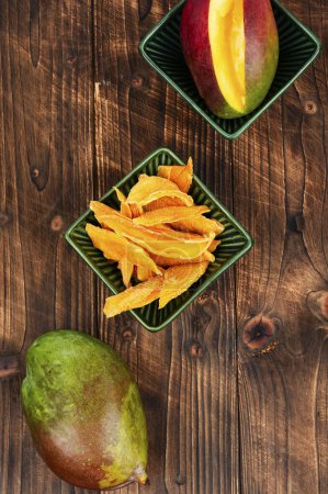 Téléchargez les photos : Tranches de mangue séchées sur table en bois, collation saine. - en image libre de droit