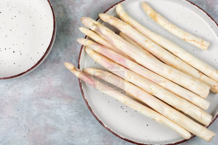 Uncooked fresh white asparagus on the kitchen table. Seasonal spring vegetables.