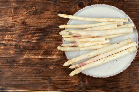 Bunch of uncooked raw white asparagus on an old rustic wooden. Space for text.