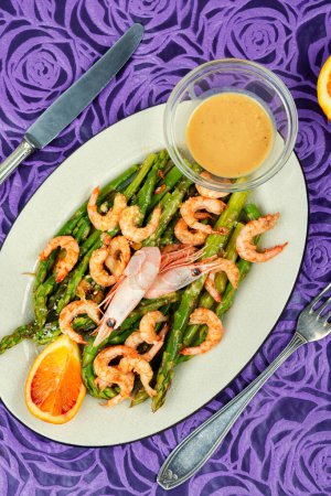 Seasonal salad with prawns and green asparagus. Cooked asparagus with prawn on the white plate.