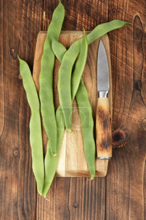 Photo for A group of fresh green flat runner beans on a wooden cutting board - Royalty Free Image