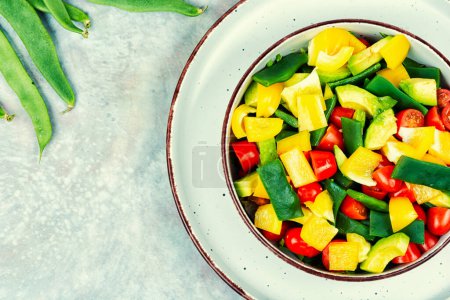 Healthy raw vegetable salad with bell pepper, tomato, avocado and runner beans. Copy space.