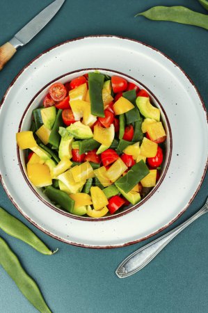 Fresh vegetable salad with bell pepper, tomato, avocado and runner beans in bowl.