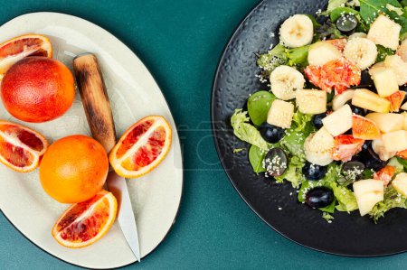 Téléchargez les photos : Salade de fruits d'orange rouge fraîche, pomme, banane et laitue. Une alimentation saine. - en image libre de droit