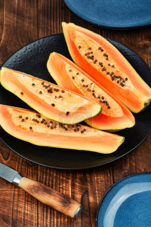 Téléchargez les photos : Tranché papaye juteuse fraîche avec couteau sur la table. Beaux fruits de papaye sur table rustique en bois. - en image libre de droit