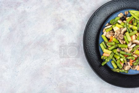 Téléchargez les photos : Salade de légumes d'asperges vertes et de champignons frits dans une assiette. Espace de copie. - en image libre de droit