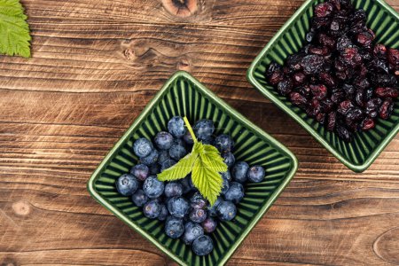 Photo for Heap of fresh blueberries and dried cranberries on rustic wooden table. Recipe place. - Royalty Free Image