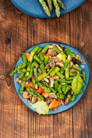 Photo for Dietary vegetarian salad of green asparagus and fried mushrooms on a plate. Flat lay. - Royalty Free Image