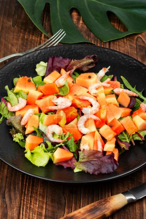 Photo for Salad with papaya, shrimp and fresh green lettuce on rustic wooden table. Healthy eating. - Royalty Free Image