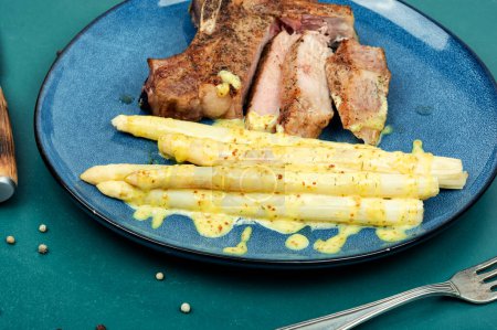 Photo for Sliced roasted meat steak with boiled white asparagus on plate. - Royalty Free Image