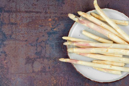 Photo for Bunch of uncooked fresh white asparagus on the kitchen table. Top view, copy space. - Royalty Free Image
