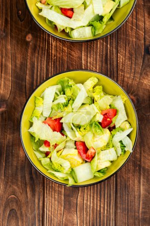 Photo for Fresh green salat of lettuce, cucumbers, tomato and avocado on wooden table background. Healthy eating. - Royalty Free Image