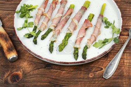 Delicious asparagus wrapped with bacon on rustic wooden table. Healthy food, ketogenic diet.