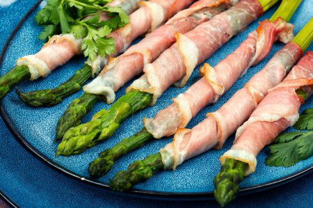 Plate with bacon wrapped asparagus on table. Close up
