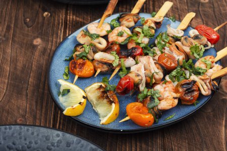 Photo for Grilled squid, fried mussels and shrimps, prawns on wooden skewers on rustic wooden table. - Royalty Free Image