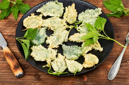 Breaded stinging nettles leaves on rustic wooden table. Hot spring greens appetizer