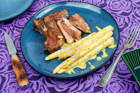Téléchargez les photos : Bifteck de viande frite juteuse aux asperges blanches bouillies. - en image libre de droit