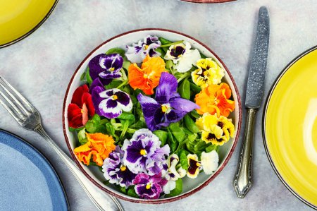 Foto de Ensalada colorida inusual decorada con flores comestibles con un tenedor. Puesta plana. - Imagen libre de derechos