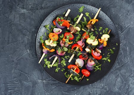 Téléchargez les photos : Délicieux shashlik de légumes frais rôtis sur des brochettes en bois sur une table de cuisine en béton. Espace pour le texte. - en image libre de droit
