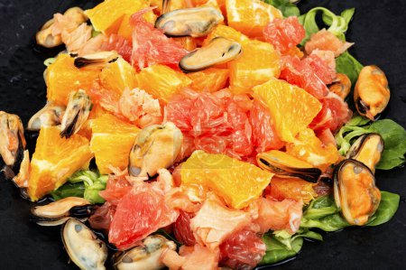 Foto de Placa con ensalada con cítricos, salmón ahumado y mejillones, alimentación saludable. - Imagen libre de derechos