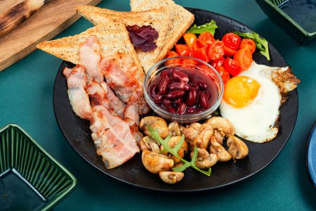 Foto de Desayuno inglés en un plato con huevos fritos, tocino, judías y tostadas. - Imagen libre de derechos