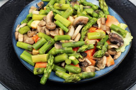 Téléchargez les photos : Salade végétarienne diététique d'asperges vertes et de champignons frits dans une assiette. Gros plan. - en image libre de droit