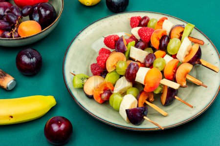 Téléchargez les photos : Brochettes de fruits juteuses à base de fruits frais sur des brochettes en bois. - en image libre de droit
