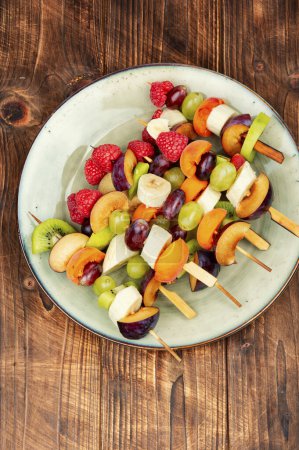 Téléchargez les photos : Brochettes de fruits faites à partir de fruits frais sur des brochettes sur une table en bois. - en image libre de droit