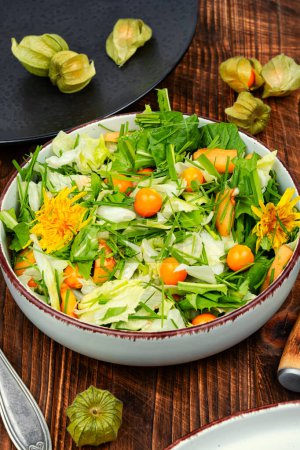 Photo for Spring salad with wild edible herbs, lettuce and physalis on rustic wooden table. - Royalty Free Image