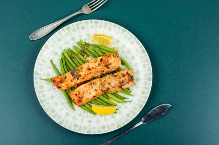 Baked or fried salmon fish with bush green beans on the plate.