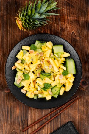 Téléchargez les photos : Assiette à salade avec ananas frais juteux et concombre sur une vieille table en bois. Alimentation saine, équilibrée, diététique. - en image libre de droit