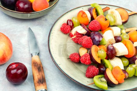 Foto de Sabrosas brochetas de frutas frescas en palos de madera. Mezcla de frutas exóticas en pinchos - Imagen libre de derechos