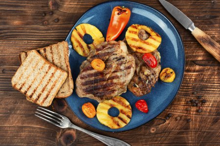 Téléchargez les photos : Viande grillée savoureuse, rôtie à l'ananas. Steak grillé et ananas sur table en bois. - en image libre de droit
