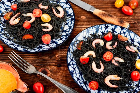 Téléchargez les photos : Spaghettis de haricots noirs végétaliens aux crevettes et tomates. Spaghettis aux pâtes noires cuites. - en image libre de droit