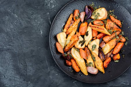 Photo for Vegan garnish of baked parsnip root, red onions, carrots and garlic. Roasted root vegetables. Space for text. - Royalty Free Image