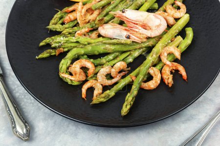 Seasonal salad with prawns, green asparagus. Fried shrimp with green asparagus spears.