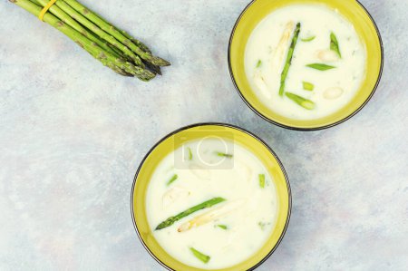 Vegan asparagus cream soup with white and green asparagus in bowl. Space for text.